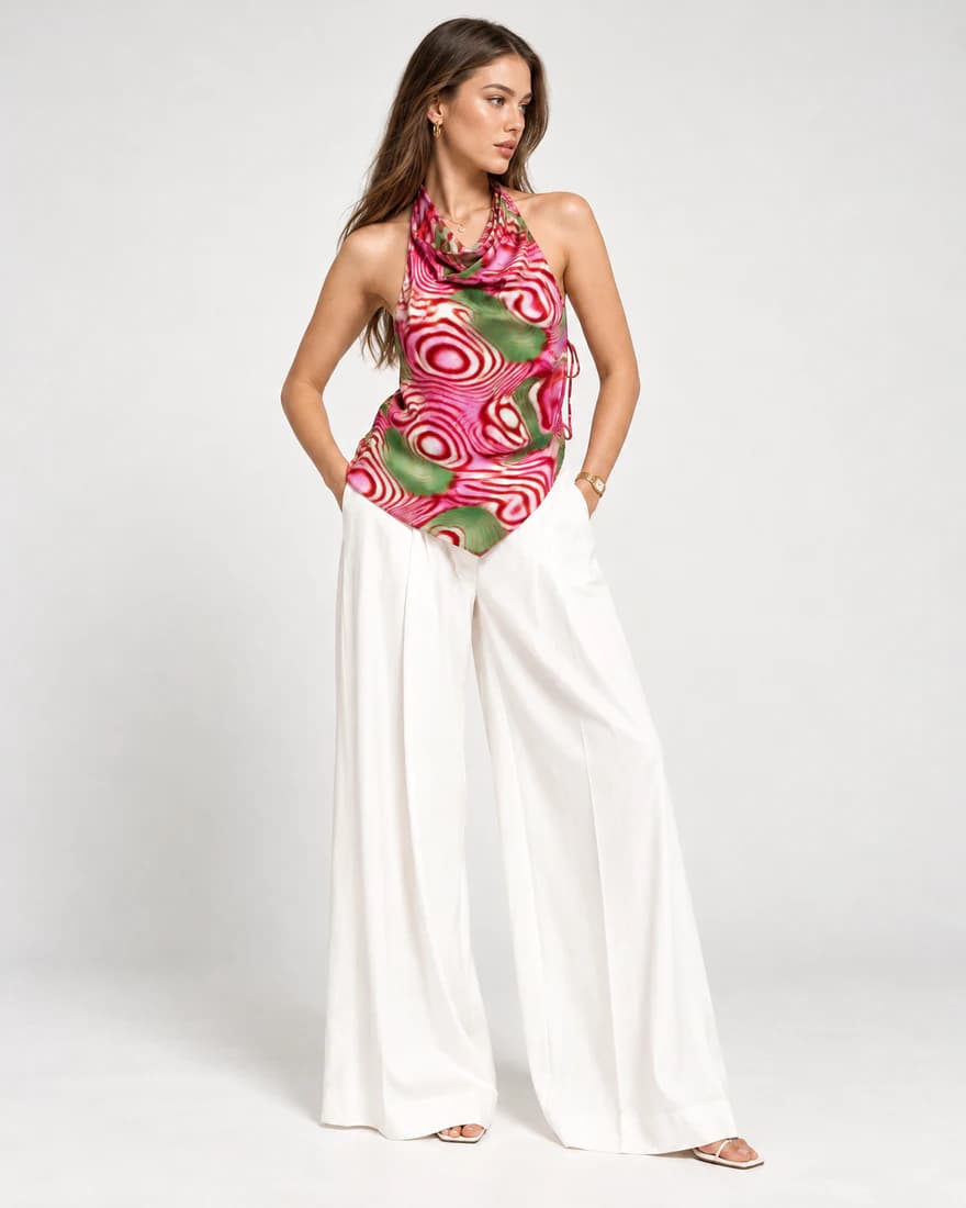 Model in a pink and green ripple print cowl-neck halter top with white trousers