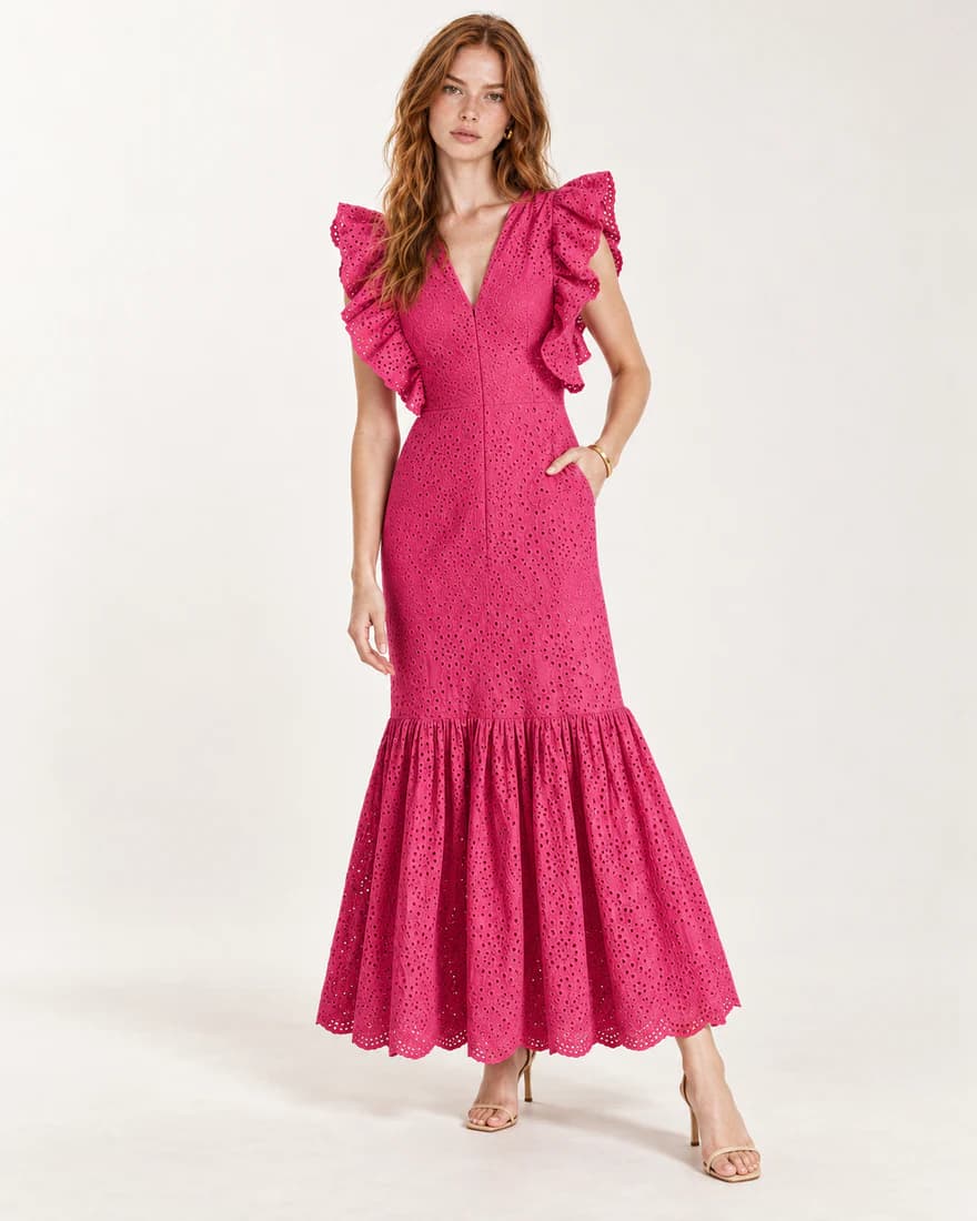 Model in a fuchsia eyelet maxi dress with ruffled sleeves and a flared hem