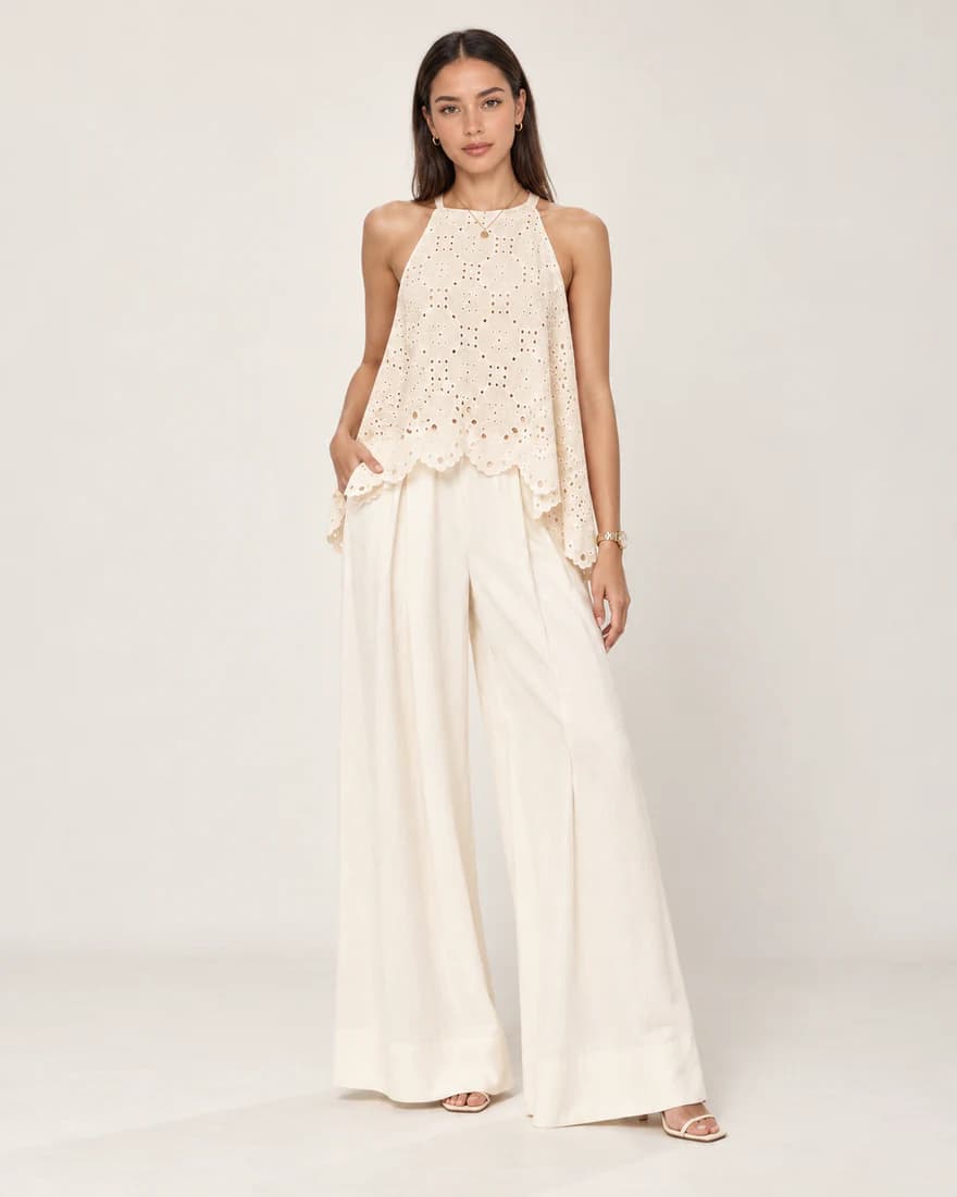 Model in an ivory eyelet halter top with cream wide-leg trousers