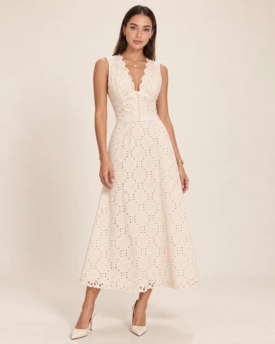 Model in an ivory eyelet sleeveless midi dress with a scalloped neckline