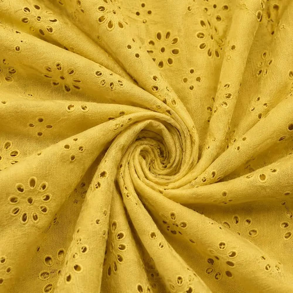 Mustard yellow schiffli eyelet fabric with floral cutwork, gathered into a swirl